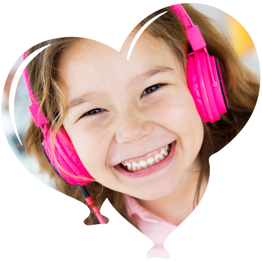 Child smiling and wearing pink headphones.